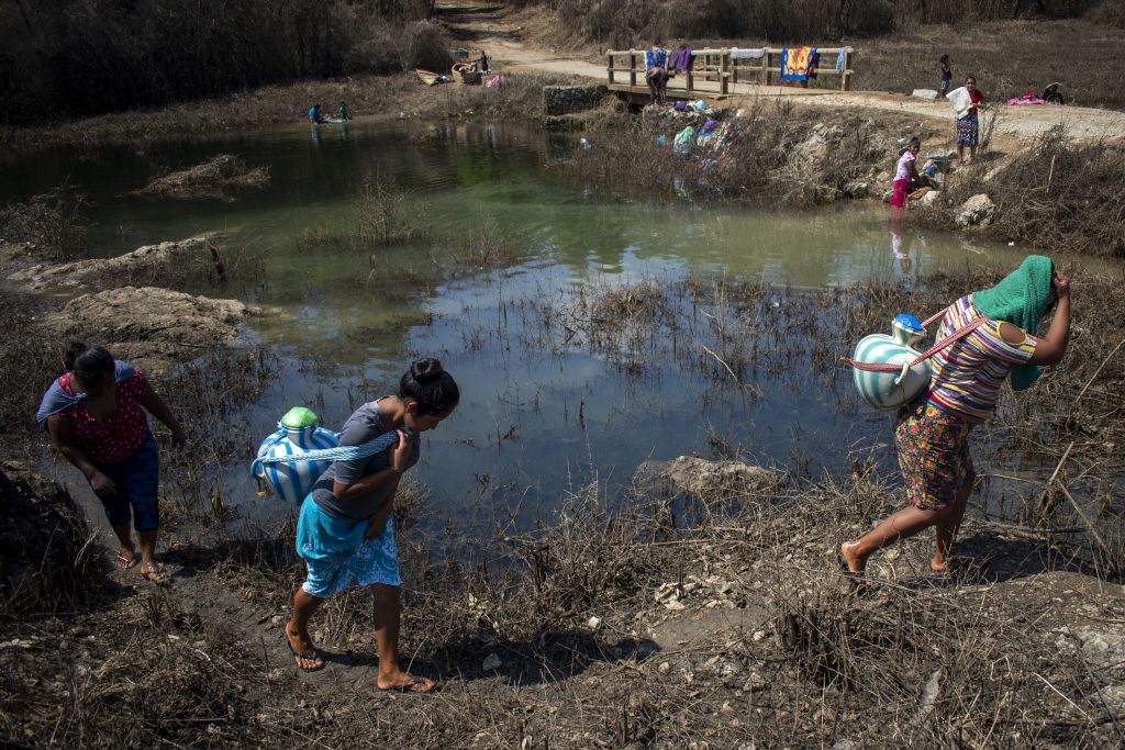 Mujeres caminan por la orilla del río Sesajal, con ropa limpia y cántaros de agua. Fotografía: Carlos Alonzo